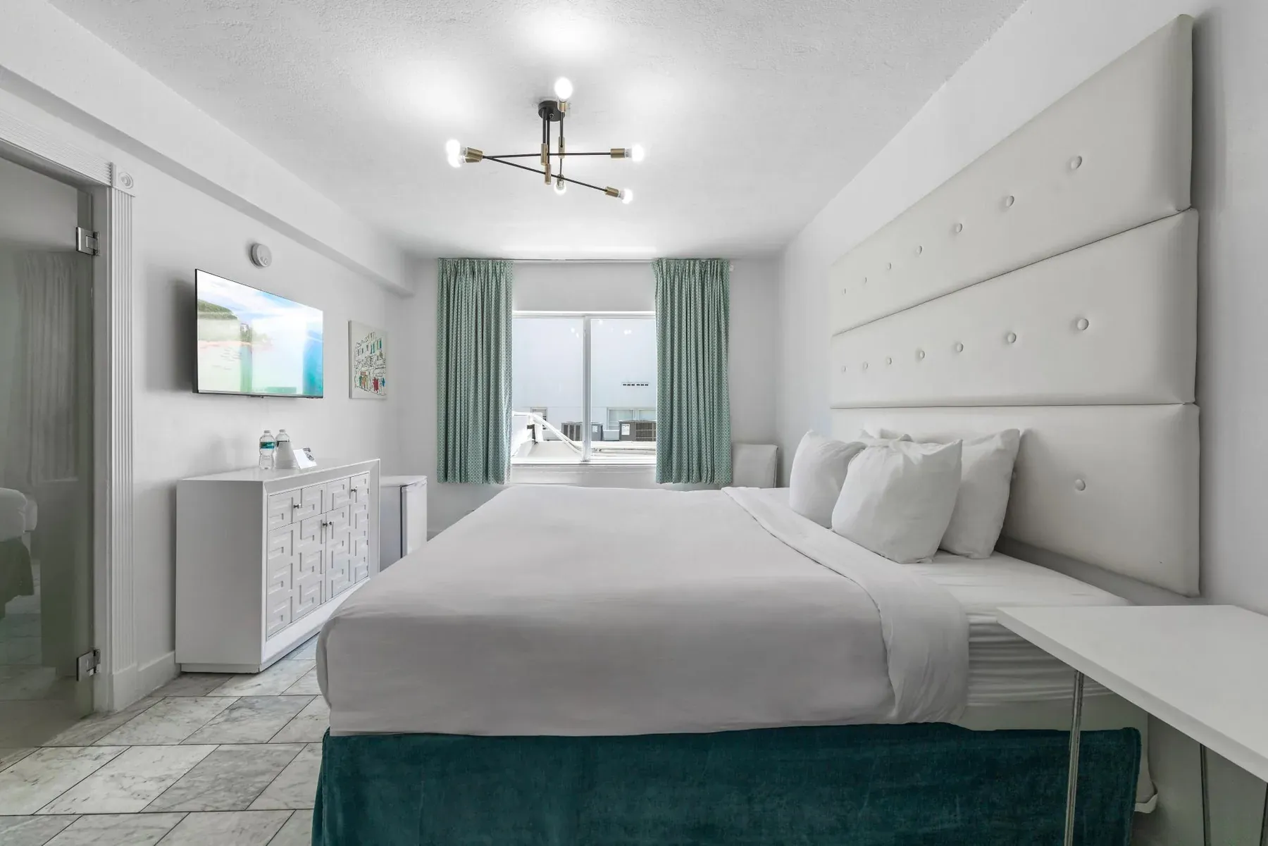 Deluxe King Room, king bed under a sputnik chandelier with the window beyond
