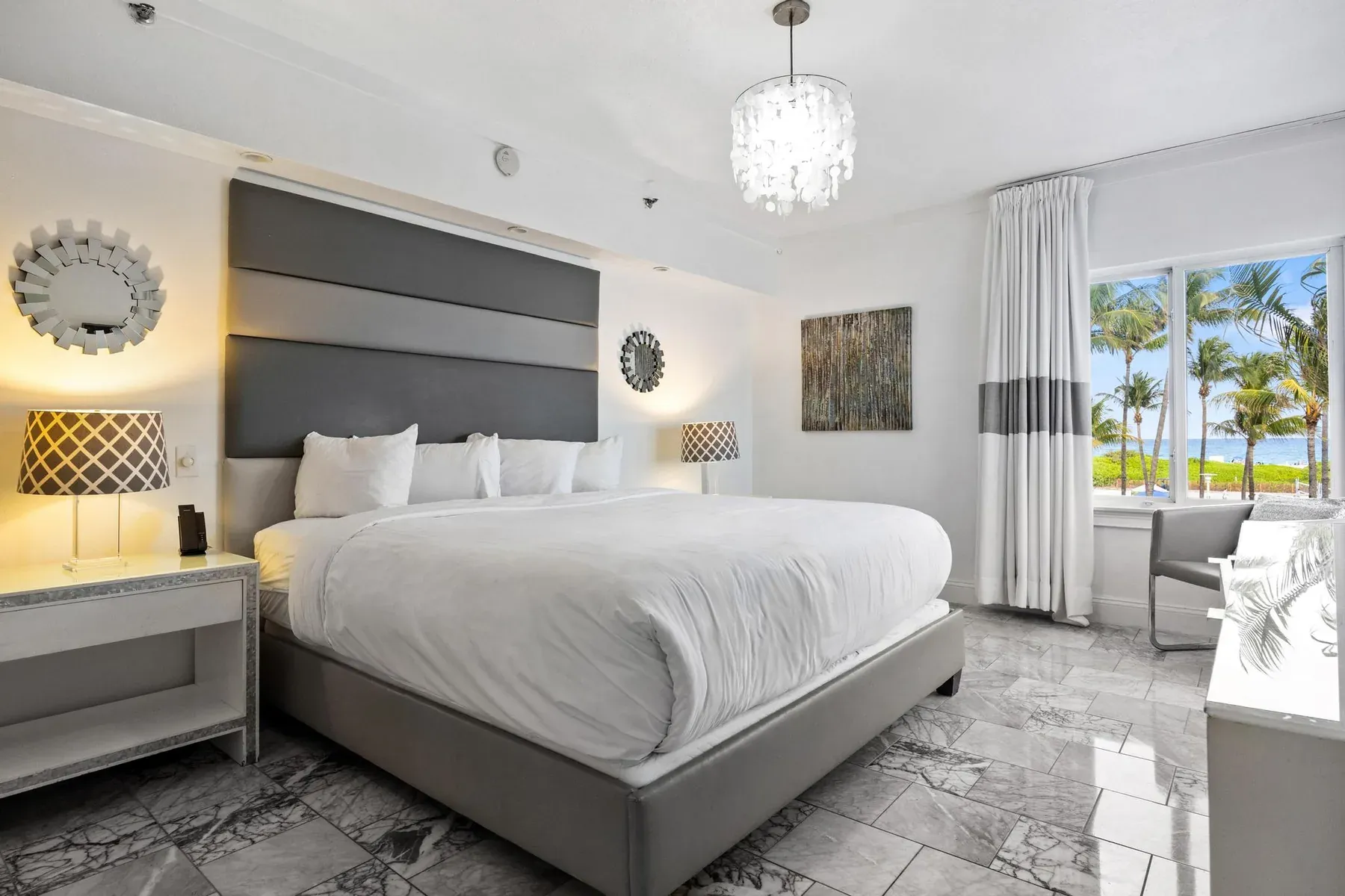 One Bedroom Suite bedroom, king bed under a chandelier with palm trees through the window