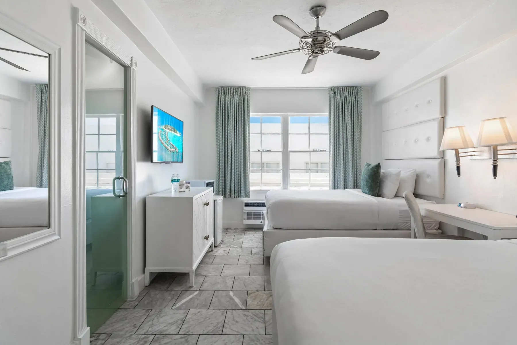 The room with the television and dresser, bathroom door open beyond