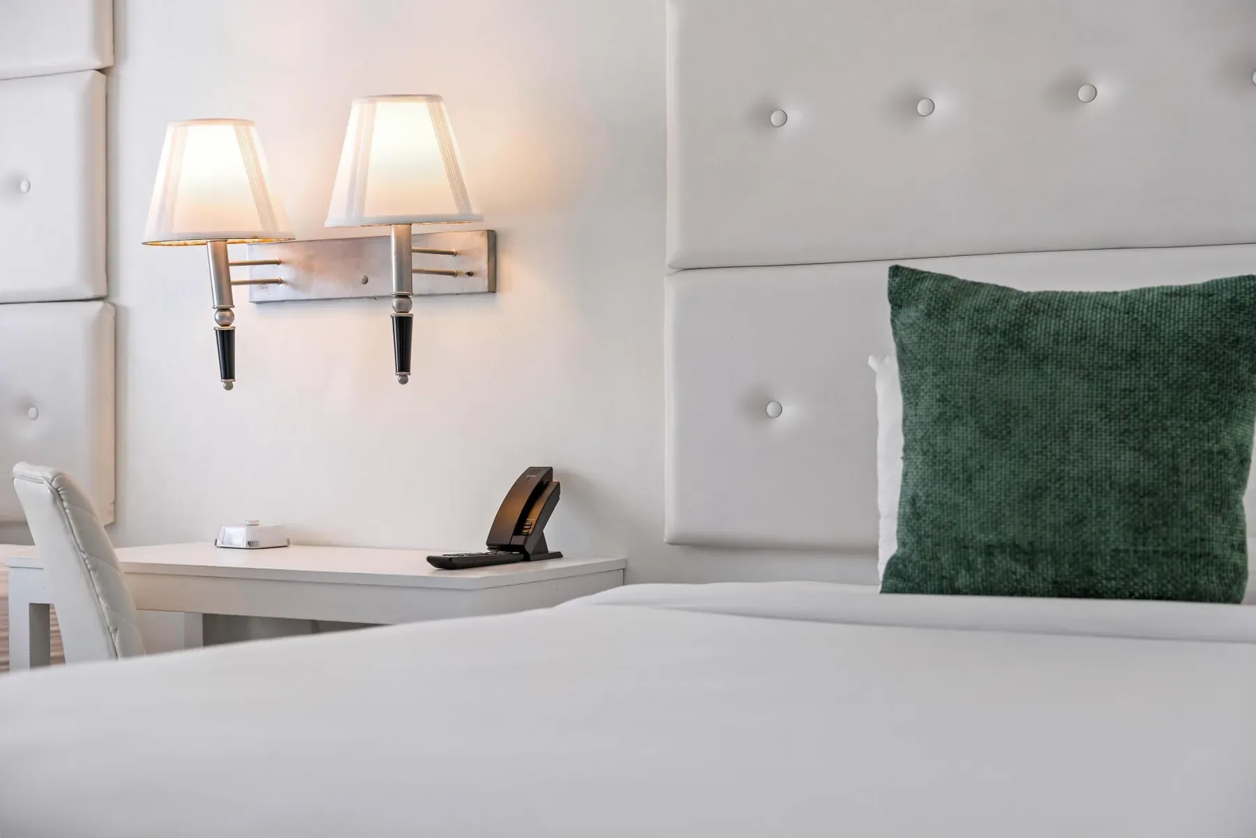 Headboard and sconce with a green accent cushion
