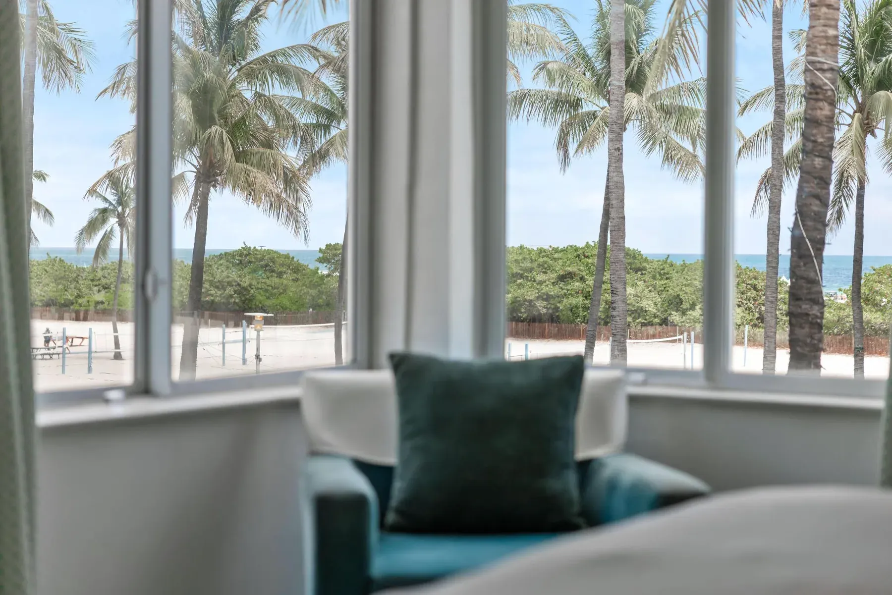 The bay window seat, palm trees and the beach directly beyond the glass
