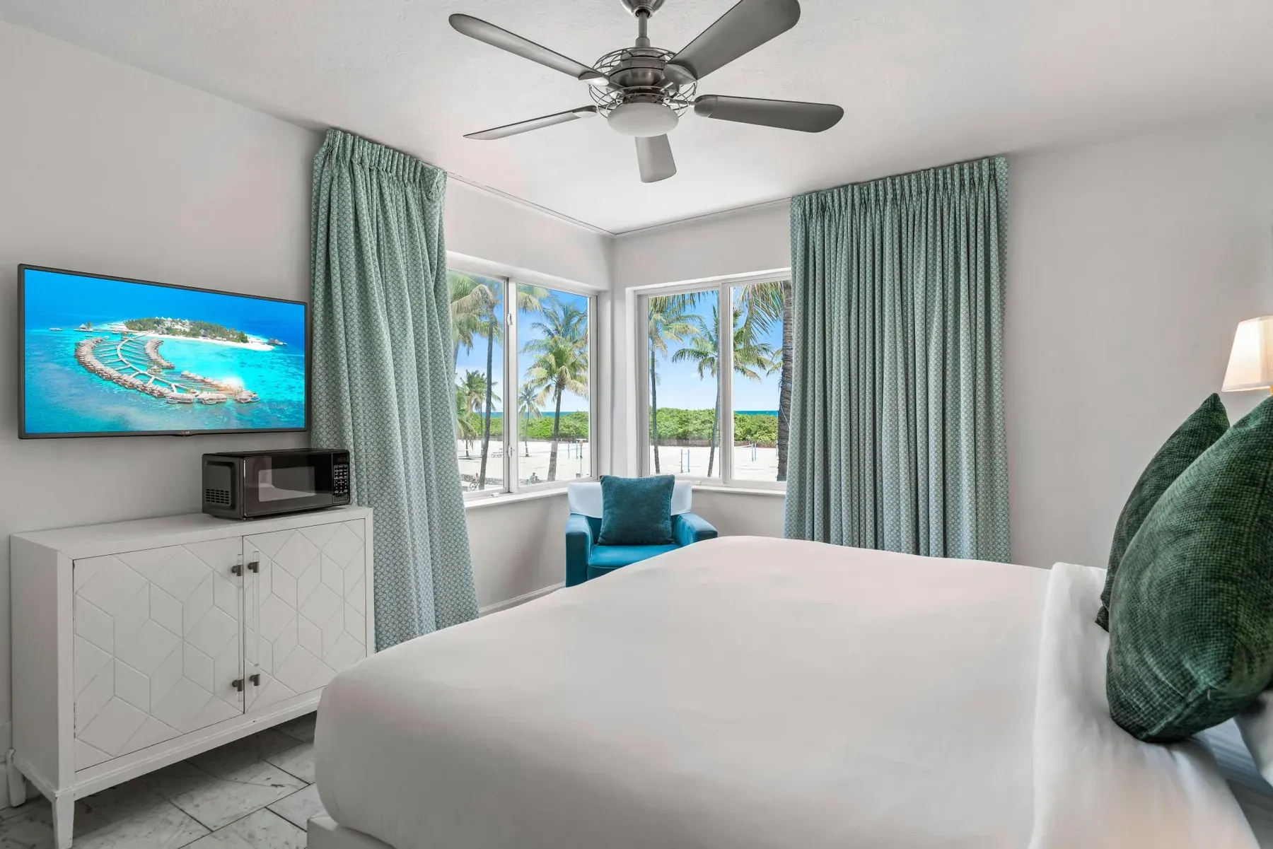 The room seen from the door, bed and dresser with the ocean windows behind