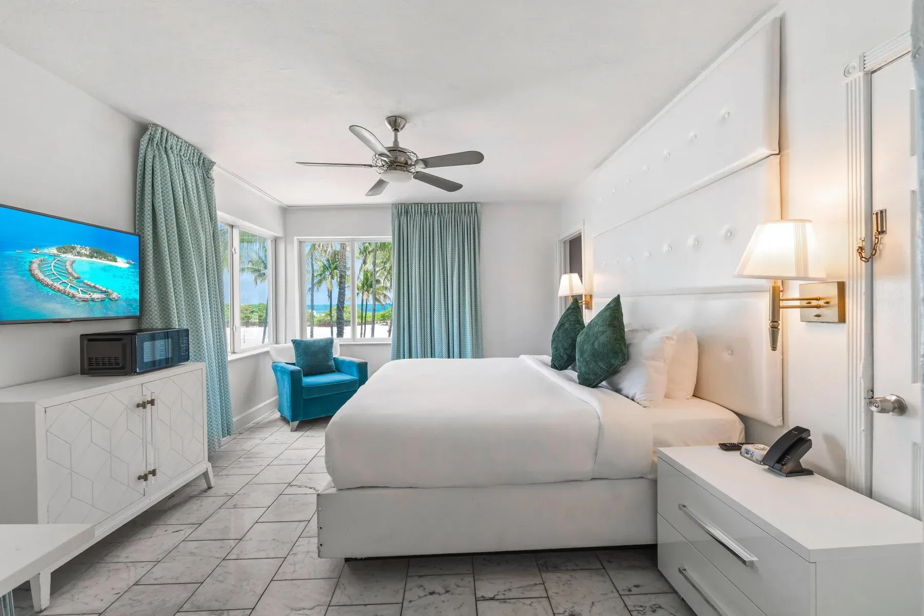 Ocean Front Room seen wide, bed, dresser and a teal armchair by the window