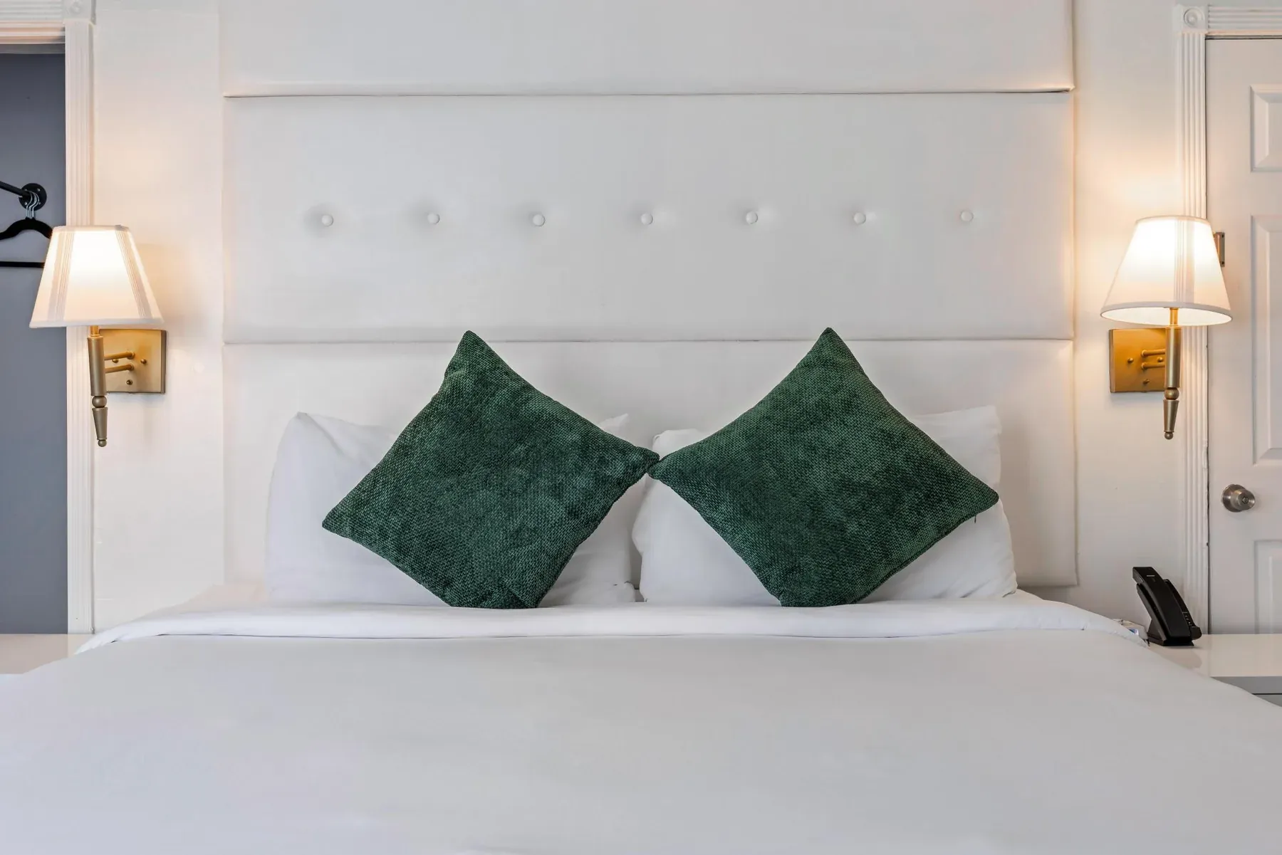The king bed head-on, buttoned headboard between two wall sconces