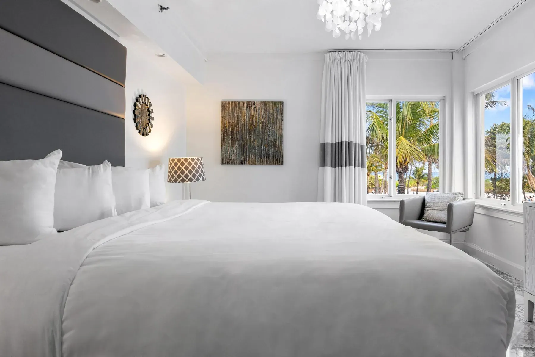 The suite bedroom seen wide, king bed facing a wall of windows
