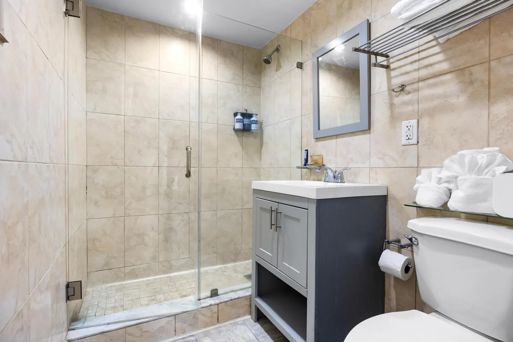 The suite bathroom, walk-in glass shower and vanity with fresh towels