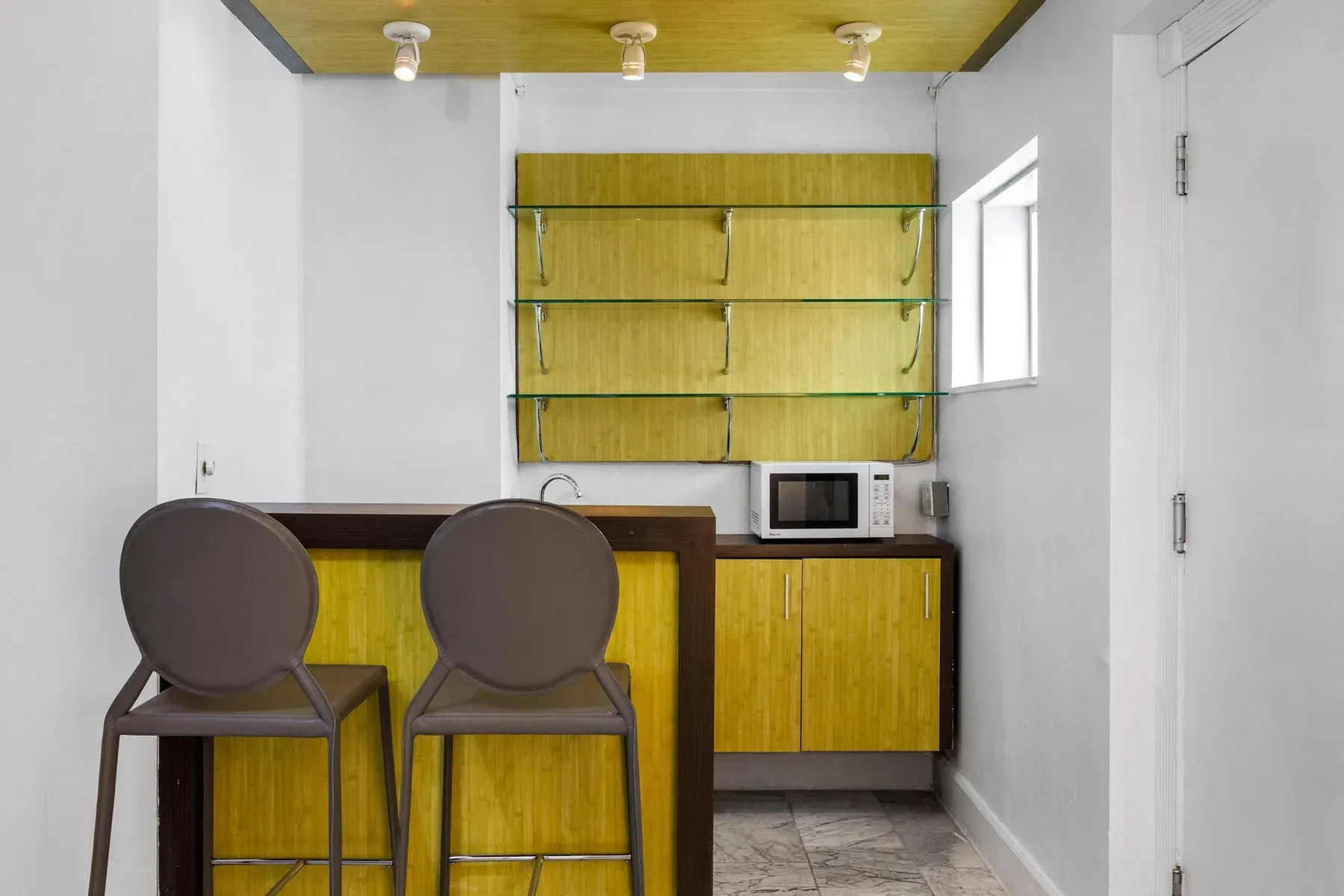 The suite kitchenette, chartreuse cabinetry with two bar stools